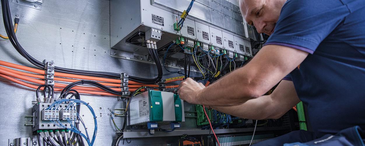 Piepenbrock Techniker in blaumen T-Shirt bei der Arbeit mit unterschiedlichen Verkabelungen