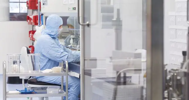 Saubere Leistung für individuelle Arzneien Reinraummitarbeiter in kompletter Schutzkleidung im Labor