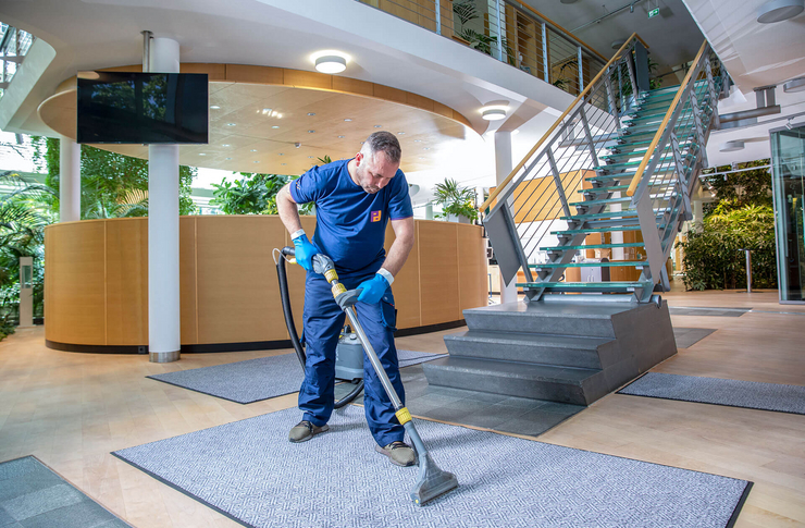Mitarbeiter der Gebäudereinigung mit Spezialsauger