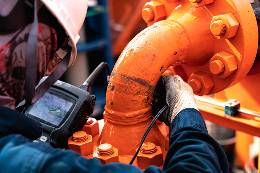 Mitarbeiter führt Druckluft-Leckageortung mit speziellen Geräten durch