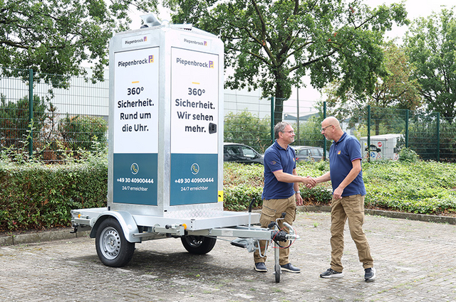 Zwei Piepenbrock Mitarbeiter geben sich neben einem mobilen Videoturm die Hand