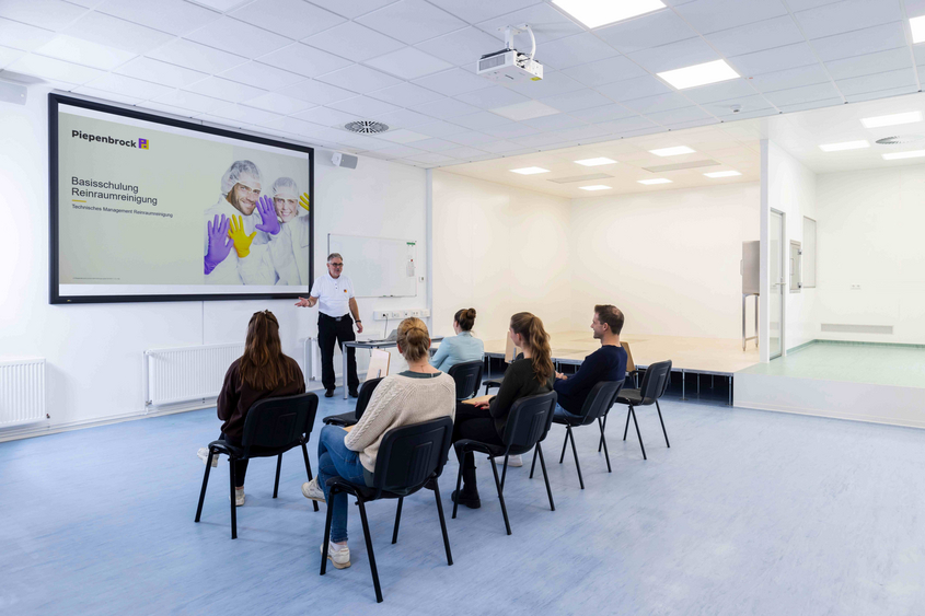 Schulungsraum mit Präsentation zur Reinraumreinigung und Teilnehmenden beim Seminar im großen Saal