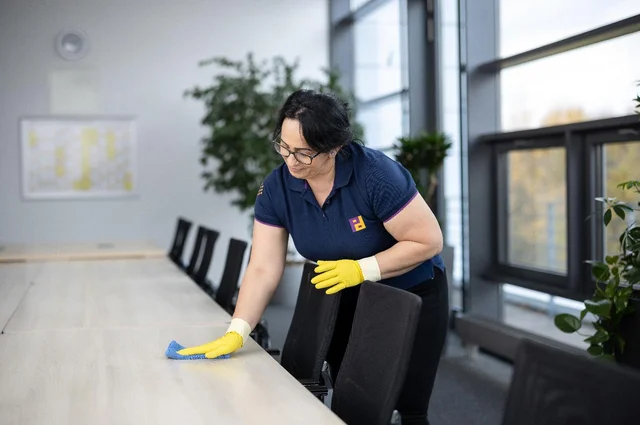 Frau wischt Bürotisch mit einem Lappen ab