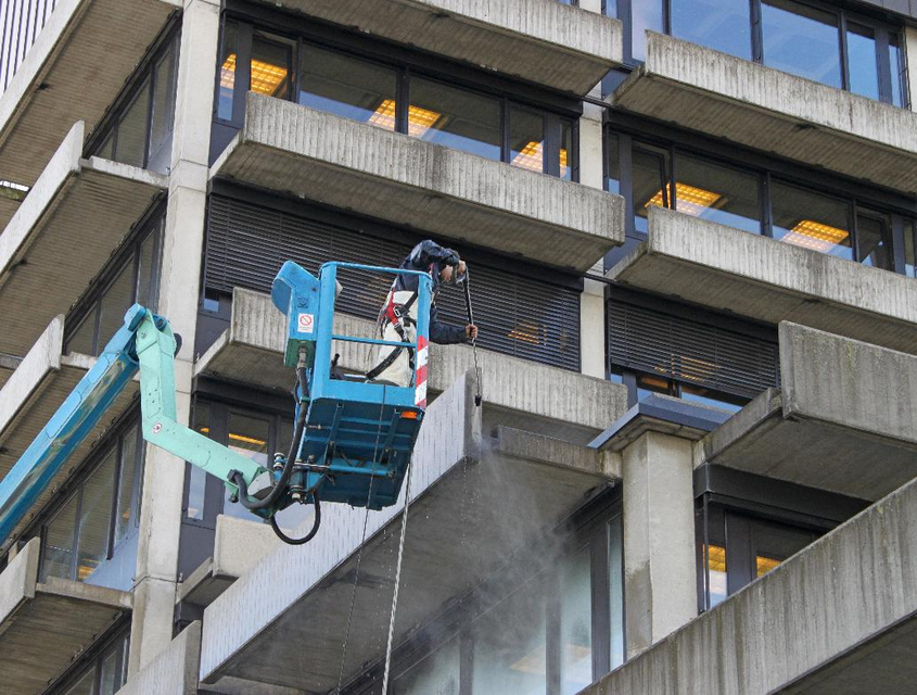 Mitarbeiter der Piepenbrock Fassadenreinigung säubert Gebäudefassade