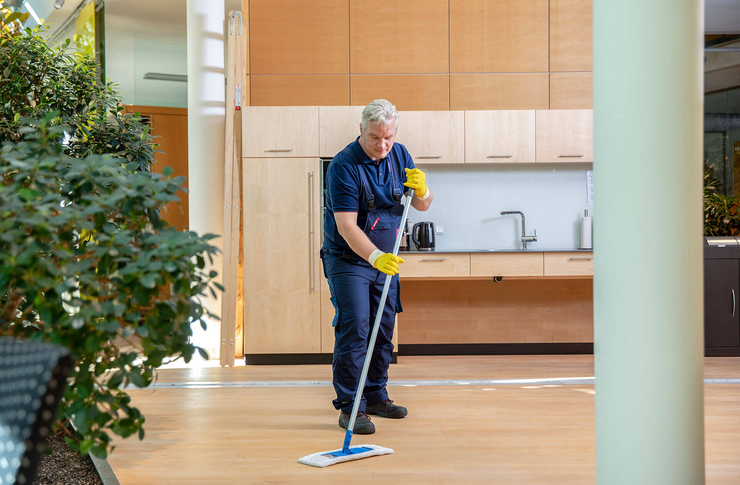 Mitarbeiter der Gebäudereinigung reinigt den Boden