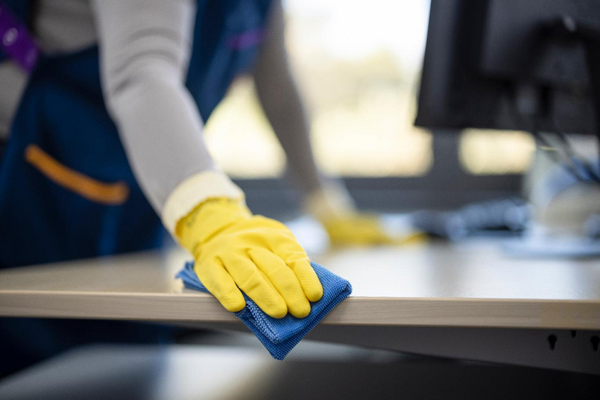 Frau reinigt Bürotisch