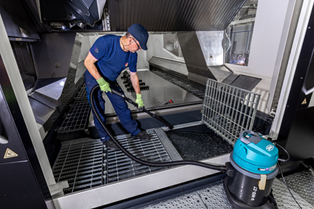 Mitarbeiter von Piepenbrock saugt den Boden mit einem Industriestaubsauger.