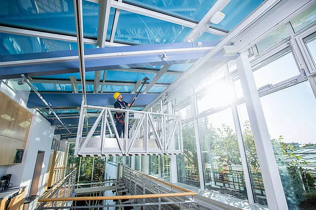 Mitarbeiter der Glasreinigung säubert Glasdach 