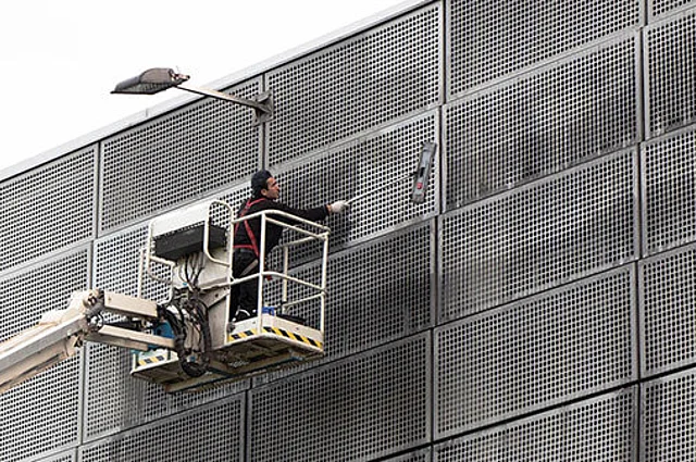 Mitarbeiter der Piepenbrock Fassadenreinigung säubert Gitterfront